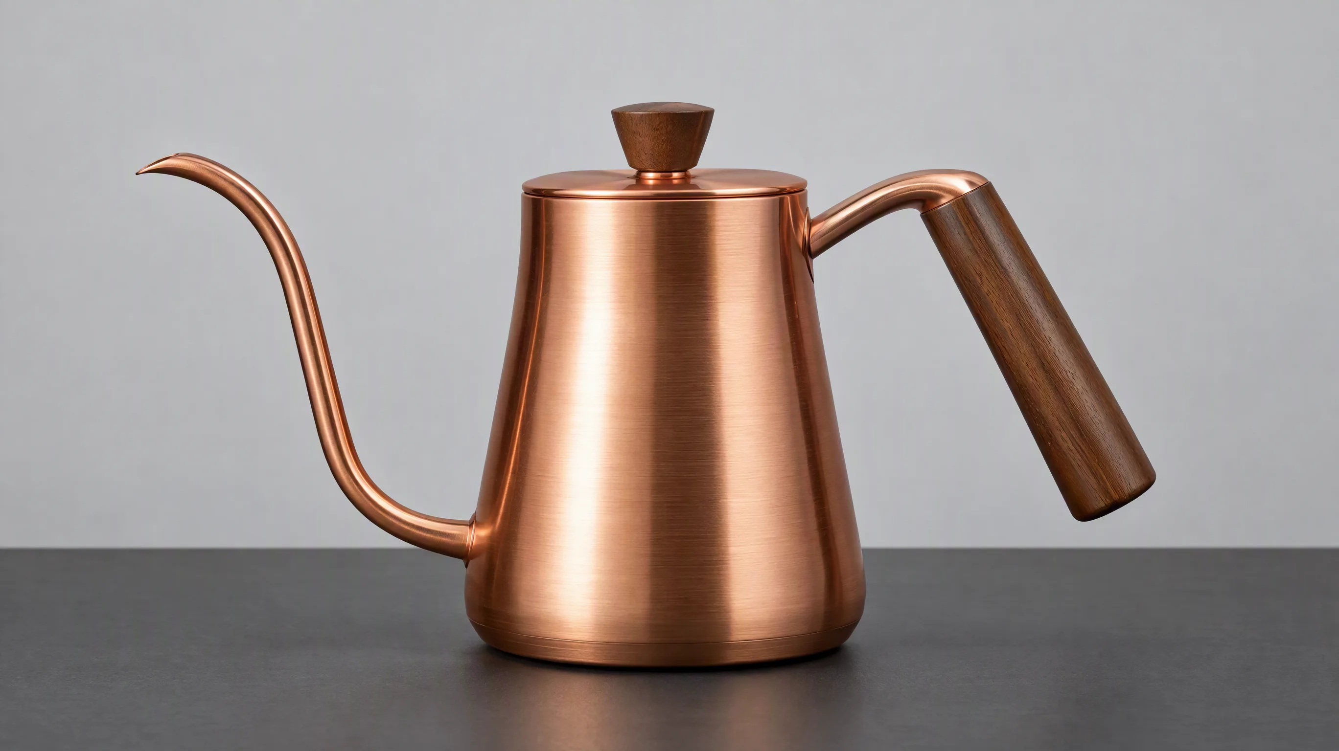 Copper kettle with curved spout, wooden handle, and round lid against a plain background