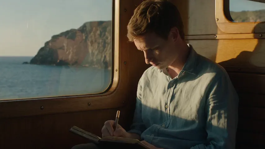 Seedance 2.5 test render of the coastal train prompt: a man writing in a notebook beside a train window with sea cliffs outside, then looking up toward the window and smiling.