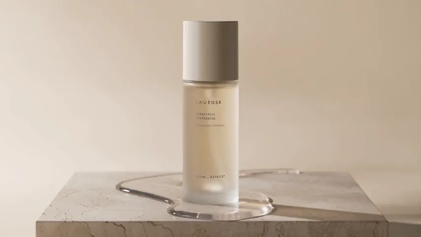 Seedance 2.5 test render of the skincare bottle prompt: a frosted glass bottle with a beige cap on a travertine block, standing in a still pool of water, with small unreadable text on its label.